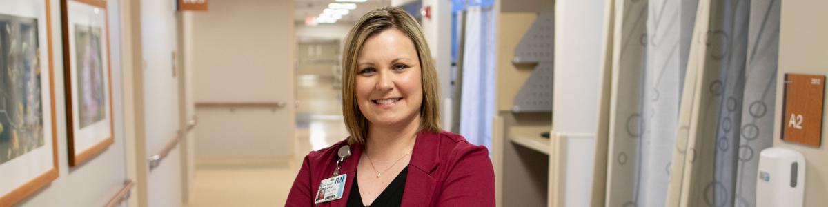 Nursing executive smiling while standing in a hospital hallway.